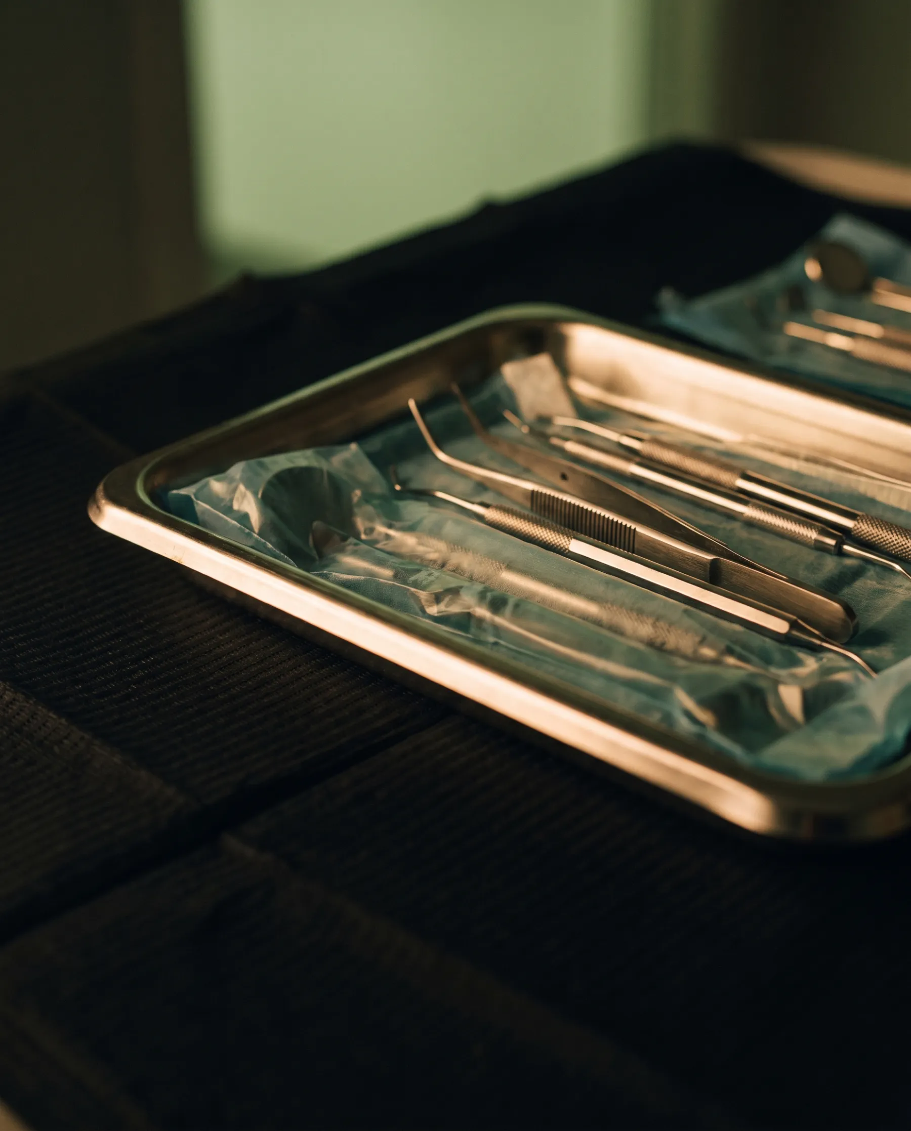 Plateau d'instruments dentaires préparé, posé sur une desserte sombre
